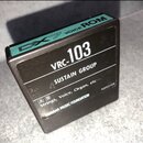 Černý čtvercový modul s nápisem VRC-103 a textem SUSTAIN GROUP. Horní hrana je tyrkysově zelená s nápisem DX7 VOICE ROM. Dole jsou uvedeny kategorie…