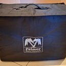 Černý textilní kryt nebo brašna s rukojetí v horní části. Na přední straně je bílé logo znázornující dvě zkřížené kladiva a nápis „Palmer Musical Ins…