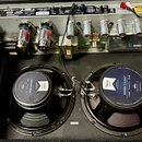 Fotografie zachycuje vnitřek kytarového komba s dvěma reproduktory a elektronickým zapojením. Horní reproduktor má na zadní straně nápisy Patriot SER…