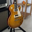 Elektrická kytara typu Les Paul s žlutým plamenovitým topem a červenými boky. Má dva humbuckery s bílými rámečky, bílý pickguard a čtyři zlaté ovláda…