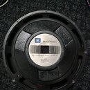 Černý reproduktor s kovovým rámem a středovým štítkem. Na štítku je logo JBL, nápis Musical Products a text JAMES B. LANSING SOUND, INC. NORTHRIDGE,…
