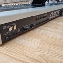 Zadní panel stříbrného klavírního syntetizátoru s černým zadním panelem. Na panelu jsou nápisy OASYS Open Architecture Synthesizer Station a KORG. Js…