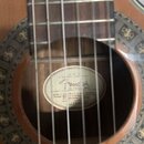 Detail akustické kytary s pohledem do ozvučovací otvoru. Uvnitř těla je nalepený oválný štítek s nápisy „Fender“, „CN-240SC NAT“ a textem „Made in ac…