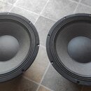 Dva černé kruhové reproduktory s papírovými membránami. Jsou umístěny vedle sebe na dlažbové podlaze. Na viditelných částech nejsou žádné značky ani…
