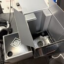 Fotografie zachycuje otevřenou šedou krabici a vedle ní samostatný šedý box. Na boku boxu je bílé logo s nápisem ZWZ a na spodní části krabice je náp…