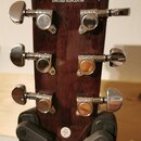 Hlava akustické kytary z tmavého dřeva s viditnou masivním kresbou. V horní části je bílý nápis Canglewood Guitar Company a pod ním UNITED KINGDOM. N…