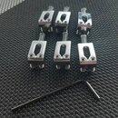 Šest kusů chromovaných kovových ladicích šroubů. K nim je přiložen jeden černý imbusový klíč. Na předmětech nejsou žádné viditelné značky ani nápisy.