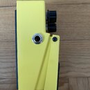 Žlutý efekt pedál z pohledu z boku. Na boku je umístěn jeden vstupní jack konektor a viditelný šroubek. V horní části vyčnívají dva černé plastové ov…