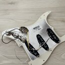 Bílá pickguard s hliníkovým stíněním a třemi černými snímači typu single-coil. Na hliníkovém povrchu je nalepený štítek s čárovým kódem a textem 7715…