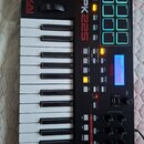 Černý MIDI kontrolér s klaviaturní klávesou a 16 podsvícenými pady. Na přístroji jsou nápisy AKAI PROFESSIONAL a MPK225. Displej zobrazuje text Prese…
