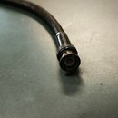 Fotografie zachycuje konec černého kabelu s kovovým konektorem. Kabel má žebrovaný povrch a zakončení je v podobě kulatého šroubovacího konektoru s c…
