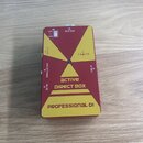 Červená kompaktní DI box s žlutými grafickými prvky. Na zařízení jsou nápisy „Ca dine“, „active DIRECT BOX“ a ve spodní části „PROFESSIONAL DI“. Jsou…