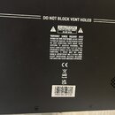 Fotografie zachycuje zadní část černého elektronického zařízení. V horní části je nápis DO NOT BLOCK VENT HOLES. Uprostřed se nachází varovný štítek…
