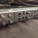 Stříbrno-černý audio mixér s několika ovládacími knoflíky a vstupy. Na předním panelu jsou viditelné nápisy CLIP, 0, -6, -12, -18, -24, CH 1, INPUT B…
