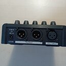 Zadní strana černého elektronického zařízení s pěti ovládacími knoflíky v horní části. Jsou zde tři konektory s popisky POWER, OUTPUT a MIC INPUT. U…