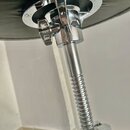 Detail spodní části sedáku hudebního taburetu s chromovaným kovovým stojanem. Je vidět šroubovací mechanismus pro regulaci výšky a upevňovací šrouby…