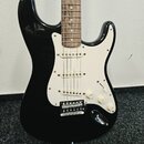 Černá elektrická kytara typu Stratocaster s bílým pickguardem a hnedým hmatníkem. Nástroj má tři snímače s bílými krytkami, jeden volič tónu a dva po…