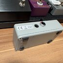 Šedý efekt pedál z kovu s matným povrchem. Na horní straně je vstup pro napájení s nápisem 9V a symboly CE a přeškrtnuté košové nádoby. Povrch pedálu…
