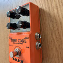 Oranžový efekt pedál s kovovým šasi a čtyřmi černými ovládacími knoflíky. Na přední straně je nápis TIME CORE DELUXE MKII a v dolní části logo NUX. J…