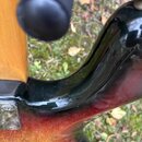 Detailní pohled na spoj hned krku a těla elektrické kytary. Tělo má tmavý lak s červeným a žlutým přechodem (sunburst) a viditelnou strukturou dřeva.…