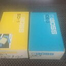 Dvě papírové krabice od efektů značky BOSS. Levá krabice je žlutá s nápisy BOSS, SD-1 a SUPER OverDrive. Pravá krabice je modrá s nápisy BOSS, CE-3 a…
