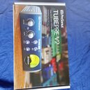 Fotografie znázorňuje krabici s produktem PreSonus TubePre V2. Na obalu je zobrazen modrý jednokanalový předzesilovač s ovládacími prvky Drive, Gain…