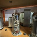 Detailní záběr na elektronovou lampu osazenou v přístroji s oranžovým povrchem. Na skle lampy je bílý nápis PM a pod ním označení EL84. V pozadí jsou…