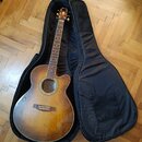 Akustická kytara s barevným přechodem od žluté k tmavě hnědé, umístěná v černém polstrováním obalu. Na hlavě hmatníku je viditelné logo Epiphone. Nás…