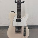 Elektrická kytara s bílým trupem a hnědým hmatníkem. Má bílý pickguard, jeden snímač typu humbucker u kobylky a jeden snímač s bílým krytem v krkovém…