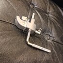 Stříbrný kovový držák na mikrofon s přivrtěvacím mechanismem a knurlovanou rukojetí. Na boku je viditelný nápis "K&M". Povrch vykazuje mírné známky p…