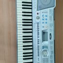Světle šedý elektronický klavír s plastovým korpusem a dvěma integrovanými reproduktory. Na přístroji jsou viditelná loga YAMAHA a označení modelu PS…