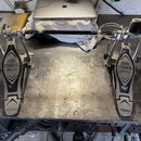 Dvojpedál na bicí buben z kovového materiálu s černými plátmi. Na obou plátích je nápis IRON COBRA 200 a v dolní části logo TAMA. Povrch plátů vykazu…