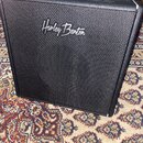 Černý kytarový kombozesilovač s povrchem z texturovaného vinylu. V horní části je umístena přenosná rukojeť a uprostřed čelní strany bílý nápis Harle…
