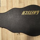 Černý tvrdý kufýr na kytaru s texturovaným povrchem. V horní části je umístěn zlatý nápis GRETSCH. Kufýr má zlaté kovové zapínání a úchyty.