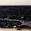 Tmavě fialová elektrická kytara v černém tvrdém kufru s plyšovou výstělkou. Na hlavě hmatníku je nápis STEREO GRAIN a na hmatníku viditelné logo znač…