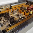 Fotografie zachycuje vnitřek elektronického zařízení v hliníkovém šasi. Uvnitř jsou vidět základní desky s osazenými součástkami, několik zlatavých v…