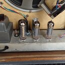 Fotografie zachycuje vnitřek reproduktorového boxu s instalovaným elektronickým zapojením. Na kovové základní desce jsou umístěny tři elektronky, jed…