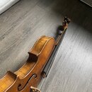 Hnědý smyčcový nástroj z dřeva s lakovaným povrchem. Na těle jsou vidět oděrky a známky opotřebení laku. Nástroj nemá žádné viditelné značky ani nápi…