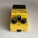 Žlutý efekt pedál s nápisy SUPER OverDrive SD-1. Na horní části jsou označení INPUT a OUTPUT se šipkami. Přístroj má tři černé ovládací knoflíky, z n…