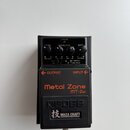 Černý kytarový efekt pedál s nápisy Metal Zone a MT-2w. Na horní části jsou tři ovládací knoflíky s popisky LEVEL, EQUALIZER a DIST, kontrolka CHECK…