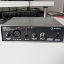 Stříbrné USB audio rozhraní značky steinberg, model UR12. Na předním panelu jsou dva ovratové knofíky pro INPUT 1 GAIN a INPUT 2 GAIN, jeden větší kn…