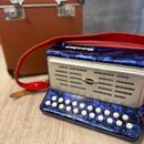 Modrý akordeon s povrchem imitujícím mramor a stříbrným kovovým maskováním. Na středu maskování je oválný nápis dellicia a na horní hraně nástroje je…