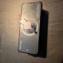 Černý efekt pedál s kovovým šasi a stříbrným ovládacím knoflíkem. Na horní části je nápis VOLUME a OUT, ve spodní části nápisy IN a logo MB Pedals. V…
