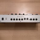 Zadní strana bílého syntetizátoru s dřevěnými bočními panely. Na horní části je nápis erica synths. Panel obsahuje napájecí spínač s označením ON, ko…