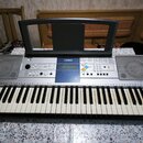 Stříbrný digitální klavír s černými a bílými klávesami. Na horní části je vlevo i vpravo integrovaný reproduktor a uprostřed nápis YAMAHA nad modrým…
