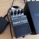Kytarový efekt pedál stříbrné a černé barvy. Na horní části je nápis Metal Core ML-2 a logo boss. Pedál má čtyři ovládací knoflíky s popisky MIN a MA…