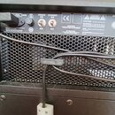 Detail zadní strany černého komba s kovovou mřížkou. V horní části jsou dva přepínače s nápisy POWER ON/OFF a STANDBY ON/OFF, pojistka s označením FU…
