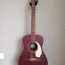 Akustická kytara v matové vínové barvě s krémovým pickguardem. Na hlavě hmatníku je bílý nápis Fender. Uvnitř ozvučovacího otvoru je vidět štítek s l…