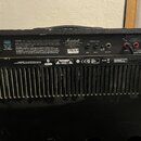 Zadní strana černého kytarového komba. Na horním panelu je bílý nápis Marshall a označení MODEL: MA100C. Jsou zde vidět konektory pro Mains input, Ef…