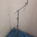 Stříbrný kovový mikrofonní stojan s trojnožkou a výsuvným ramenem. Na horním konci je umístěn černý držák mikrofonu. Povrch stojanu vykazuje známky b…
